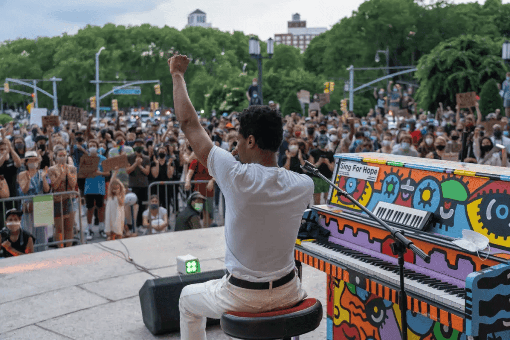 Man with piano beside him greeting the audience