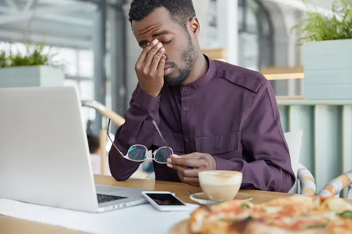 man looking overwhelmed and working on laptop